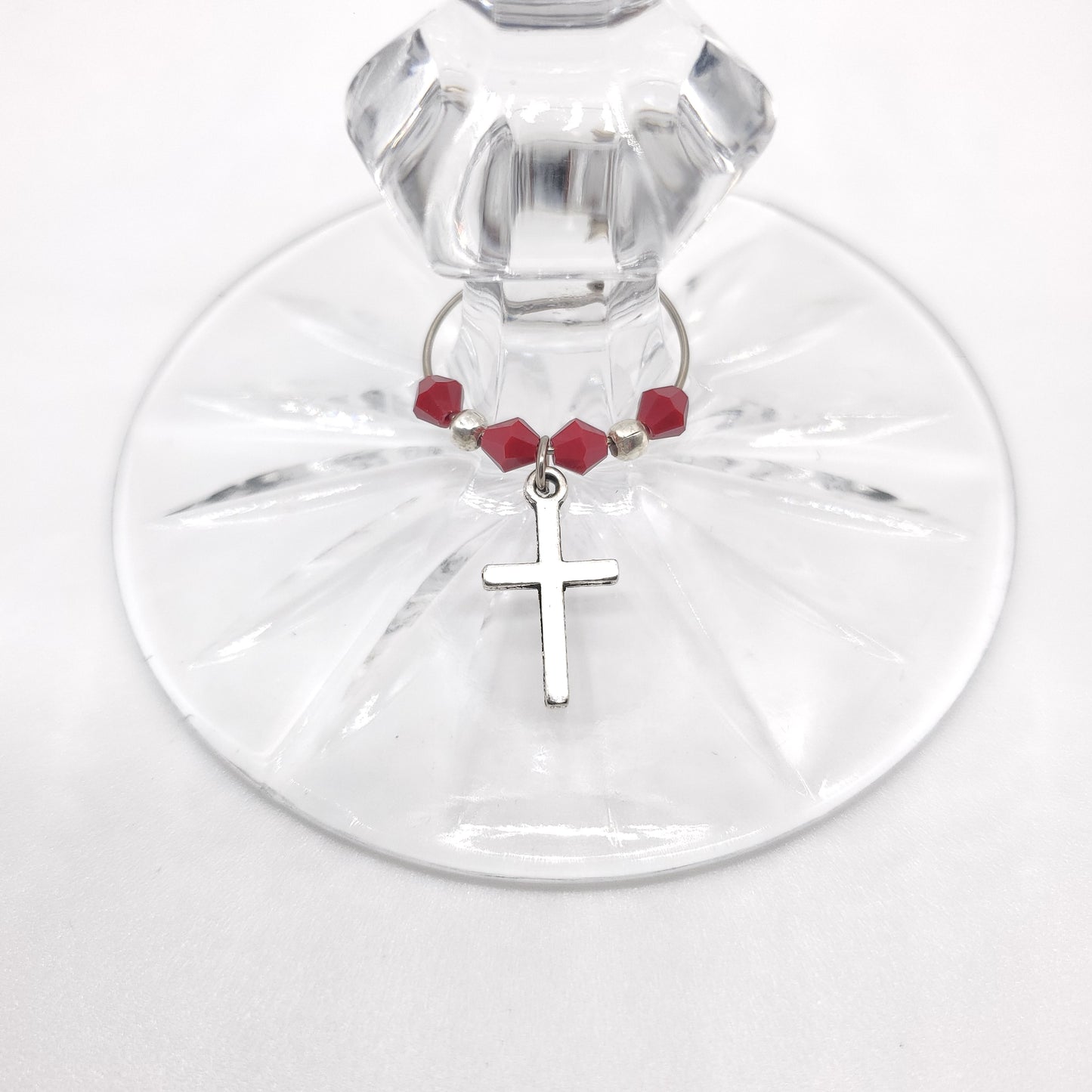 cross wine charm on a glass with red beads